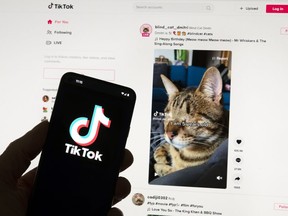The TikTok logo is seen on a mobile phone in front of a computer screen which displays the TikTok home screen, Saturday, March 18, 2023, in Boston.