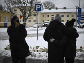 People gather by a makeshift memorial in front of the Viertola School in Vantaa, in the north of the Finnish capital Helsinki, on April 3, 2024, one day after a 12-year-old opened fire inside the school, killing a classmate and seriously injuring two other children.