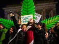 Marijuana smokers celebrate in front of a giant mock marijuana plant at a demonstration outside Berlin's Brandenburg Gate to mark the coming into force in Germany on April 1, 2024 of a law allowing adults to carry up to 25 grams of dried cannabis and grow up to three marijuana plants at home.