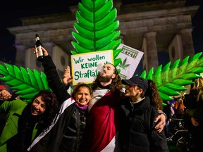 Marijuana smokers celebrate in front of a giant mock marijuana plant at a demonstration outside Berlin's Brandenburg Gate to mark the coming into force in Germany on April 1, 2024 of a law allowing adults to carry up to 25 grams of dried cannabis and grow up to three marijuana plants at home.