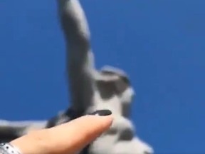 Screenshot of finger pretending to tickle statue that is in the distance.