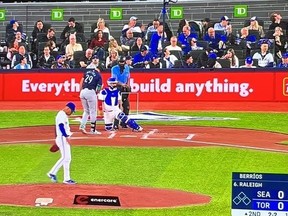 TV showing Blue Jays/Mariners game featuring pitcher, batter and fans behind home plate.