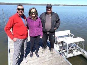 Ken and Janet Reid and Gerry Sutton, right, stand on a dock in the Rideau Canal where they rescued a pair of canoeists north of Kingston Mills, Ont., on Sunday, April 14, 2024. Next to the trio is the paddleboat Sutton used to paddle to the canoeists' aid.