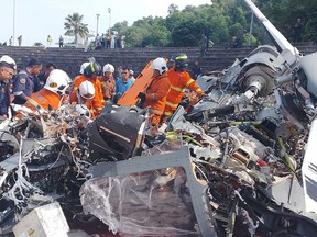 This handout picture taken and released on April 23, 2024 by Perak's Fire and Rescue Department shows rescuers inspecting the crash site after two military helicopters collided in Lumut in Malaysia's Perak state.
