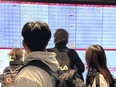 Travelers look at a departure information board at Pierre Elliott Trudeau International Airport in Montreal, Friday, Dec. 23, 2023. The authority overseeing the Montreal airport is rolling out a nearly $4-billion plan to reduce congestion and improve access.
