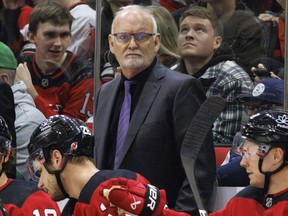FILE - New Jersey Devils head coach Lindy Ruff, center, looks toward the ice during the third period of an NHL hockey game against the Carolina Hurricanes in Raleigh, N.C., Feb. 10, 2024. Ruff is returning to Buffalo for a second stint as coach of the Sabres. General manager Kevyn Adams announced the hiring Monday, April 22, 2024.