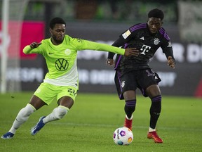 Wolfsburg's Ridle Baku, left, and Bayern's Alphonso Davies battle for the ball during the German Bundesliga soccer match between VfL Wolfsburg and Bayern Munich at the Volkswagen Arena, Wolfsburg, Germany, Wednesday, Dec. 20, 2023. Count the Vancouver Whitecaps among those watching Alphonso future with Bayern Munich with interest. The Whitecaps will benefit from any future sale, thanks to a sell-on clause negotiated in the Canadian star's sale to the German powerhouse in July 2018.