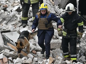 Ukrainian rescuers work with a search dog among the rubble of a destroyed building