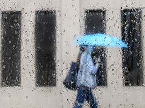 An early spring storm is bringing high winds and heavy rain to parts of Ontario as Environment Canada warns of significant snowfall in other parts of the province. A pedestrian walks on a rainy day in Toronto on Friday, June 18, 2021.