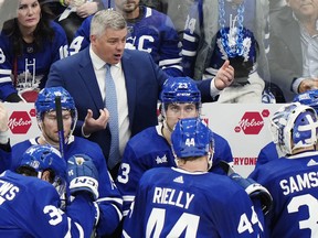 Ex-Toronto Maple Leafs head coach Sheldon Keefe talks to his players on the bench.