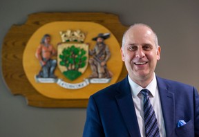 Stephen Holyday poses for a photo with the Etobicoke coat of arms in his office