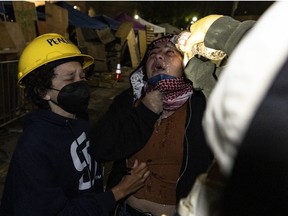 A pro-Palestinian protester (centre) is being taken care of after being maced at a pro-Palestinian encampment set up on the campus of the University of California Los Angeles (UCLA) as clashes erupt, in Los Angeles on May 1, 2024.