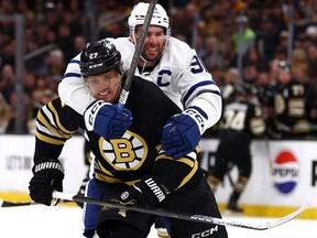 Hampus Lindholm of the Boston Bruins protects the puck from John Tavares of the Maple Leafs during the second period of Game 5 at TD Garden on April 30, 2024 in Boston.