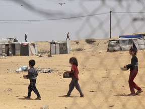 Displaced Palestinian children carry containers with food.