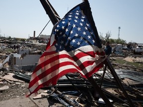 An American flag is seen as residents go through tornado damage.