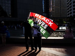 A person holds a Black Lives Matter flag as people gather outside the Hennepin County Government Center on May 23, 2021 in Minneapolis, Minnesota.