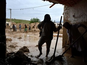 Afghan men shovel mud from a house following flash floods after heavy rainfall at a village in Baghlan-e-Markazi district of Baghlan province on May 11, 2024.