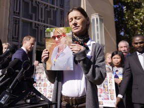 FILE - Catherine Berthet, of France, closes her eyes as she holds a photo of her deceased daughter Camille Geoffroy, in front of other families that lost loved ones to crashes of the Boeing 737 Max airliner outside the federal court in Fort Worth, Texas, Thursday, Jan. 26, 2023. Relatives of passengers who died in two Boeing Max crashes are pushing federal officials to prosecute the company, but they're not getting any promises from the Justice Department.