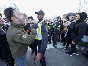 Pro-Israel protesters, left, and pro-Palestine protesters face off as police keep the two groups separate at a demonstration in front of a synagogue in Thornhill, Ont., Thursday, March 7, 2024.