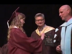Screenshot of high school graduate holding out banned book for superintendent.