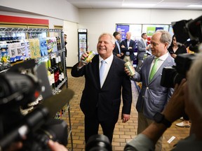 Ontario Premier Doug Ford pretends to drink from a beer can and Finance Minister Peter Bethlenfalvy holds one at an announcement saying the province is speeding up the expansion of alcohol sales, in Toronto on Friday, May 24, 2024.