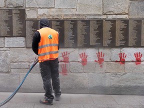 A city employee is at work to clean the "Wall of the Righteous" (Mur des Justes) covered with Red hands graffitis outside the Shoah memorial in Paris, on May 14, 2024, after the monument was vandalized overnight with the president of the Representative Council of French Jewish Institutions (CRIF) denouncing the act as anti-Semitic.