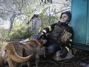 A firefighter pets a dog as he rests