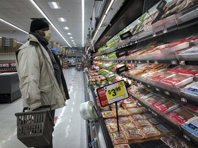 A man shops in the meat section