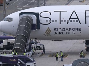 Officials gather around the Singapore Airlines Boeing 777-300ER airplane, which was headed to Singapore from London before making an emergency landing in Bangkok due to severe turbulence, as it is parked on the tarmac at Suvarnabhumi International Airport in Bangkok on May 22, 2024.