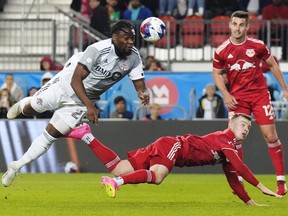 Toronto FC forward Ayo Akinola (20) heads the ball as New York Red Bulls forward Cameron Harper (17) defends and defender Dylan Nealis (12) looks on during second half MLS soccer action in Toronto on Wednesday, May 17, 2023. Canadian forward Akinola is leaving Toronto FC after agreeing to a mutual termination of his contract.THE CANADIAN PRESS/Chris Young