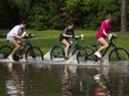 Girls ride their bikes through flood water near the bridge over Lake Houston along West Lake Houston Parkway after it was closed due to high water on either side of the thoroughfare, Saturday, May 4, 2024, in Kingwood, Texas.