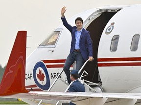 Prime Minister Justin Trudeau waves as he steps off a plane