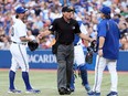 Pitcher R.A. Dickey, left, and John Gibbons of the Toronto Blue Jays argue a call against the Baltimore Orioles with umpire Angel Hernandez in the second inning during MLB action at the Rogers Centre in Toronto June 21, 2013.