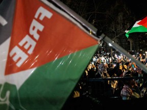 Pro-Palestinian demonstrators wave flags and hold up smartphones outside the fenced in area of an encampment on the University of Toronto campus on May 2, 2024, in Toronto.