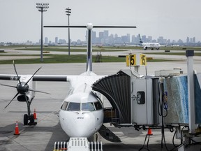 A WestJet passenger jet taxis while a WestJet turbo prop plane sits parked at a departure gate at the Calgary International Airport on Wednesday, May 31, 2023.