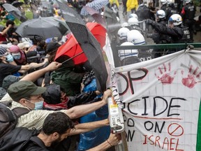 Riot police use tear gas and push away barricades that pro-Palestinian protesters used to box them in during a demonstration outside the James building at McGill University in Montreal on Thursday, June 6, 2024.