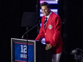 Former New England Patriots quarterback Tom Brady wears his red Patriots Hall of Fame induction jacket as he speaks during the 2024 induction ceremony.