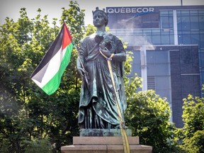 Protesters attached a Palestinian flag to the statue of Queen Victoria outside their encampment at Victoria Square in Montreal, Tuesday June 25, 2024. A city worker removed the flag later Tuesday, along with a strap that appeared to have been used in an attempt to topple the statue the previous evening.