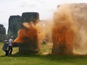activists spraying an orange substance at Stonehenge
