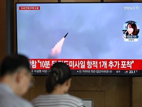 As pessoas assistem a uma tela de televisão mostrando um noticiário com imagens de um teste de míssil norte-coreano.