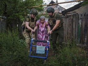 Police officers of the White Angels unit help an elderly woman walk into a van during an evacuation to safe areas, in Toretsk, Donetsk region, Ukraine, Friday, June 28, 2024.