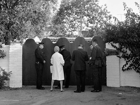 In this Aug. 5, 1962 file photo, police officers and newsmen stand at the driveway gate to the home of Marilyn Monroe after she was found dead in her bedroom. The Spanish-style one-story house is in the Brentwood area of Los Angeles.