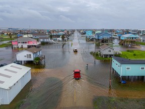 vehicles drive through flooded neighborhoods