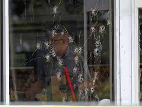 Damage can be seen to a front window law enforcement officers work the scene of a shooting at the Mad Butcher grocery store in Fordyce, Ark., Friday, June 21, 2024.