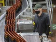 A Labatt manager watches as hundreds of bottles of Budweiser zip past on the beer brewer's production line in London, Ont., in a file photo.