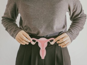 A woman holds a cutout of the female reproductive system.