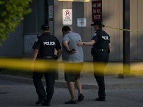 Toronto Police officers comfort a man at the scene of a shooting that left three people dead in Toronto, Monday, June 17, 2024.