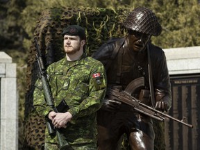 A soldier stands next to the Royal Regina Rifles statue in this April 6, 2024 handout photo during a previewing ceremony at the Saskatchewan War Memorial in Regina. It's to be unveiled Wednesday at Juno Beach at la place des Canadiens in France. The names of 488 soldiers from the infantry unit who died during the Second World War are etched into the statue's base.