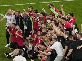 Georgia's team and staff members celebrate at the end of a Group F match between Georgia and Portugal at the Euro 2024 soccer tournament in Gelsenkirchen, Germany, Wednesday, June 26, 2024.
