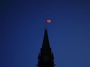 The Canadian flag catches the morning light on the Peace Tower on Parliament Hill in Ottawa on Tuesday, April 16, 2024. While the Maple Leaf unites Canadians, the red and white hold different meanings in the fashion world and among other cultures, that go beyond patriotic buntings.